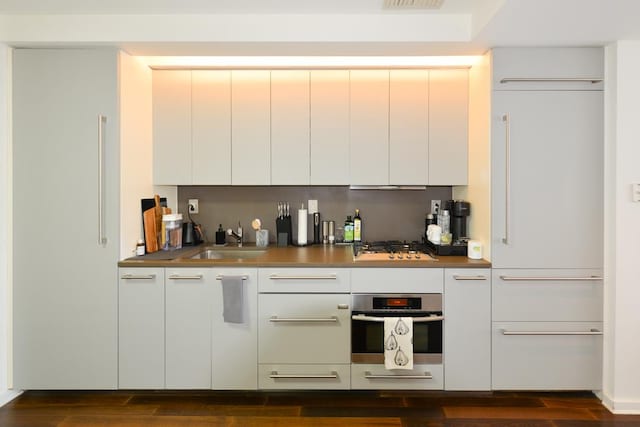 kitchen with dark wood-style flooring, stainless steel appliances, modern cabinets, and a sink