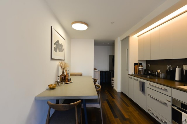 kitchen featuring stainless steel oven, dark wood-style floors, white cabinets, modern cabinets, and a sink