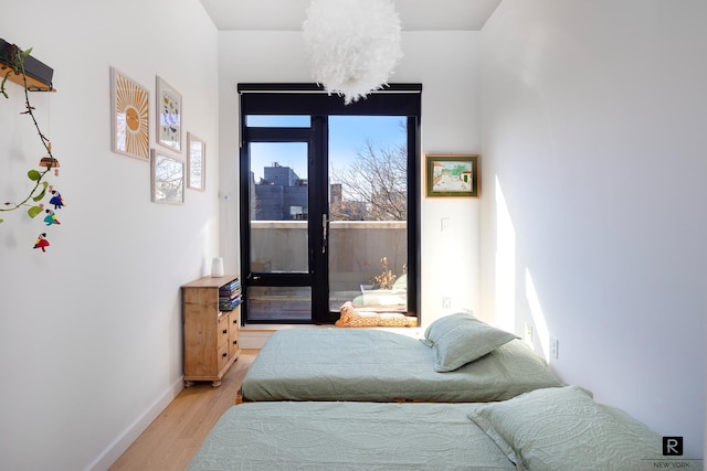 bedroom with access to outside, baseboards, and light wood-type flooring