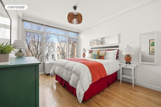 bedroom featuring light wood-type flooring, multiple windows, baseboards, and visible vents