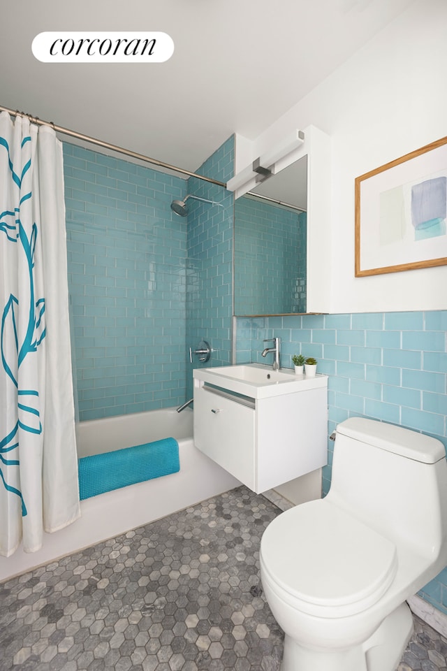 bathroom with vanity, tile walls, toilet, and shower / bath combo