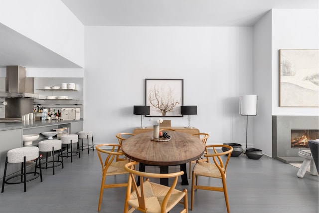 dining room with wood finished floors and a lit fireplace