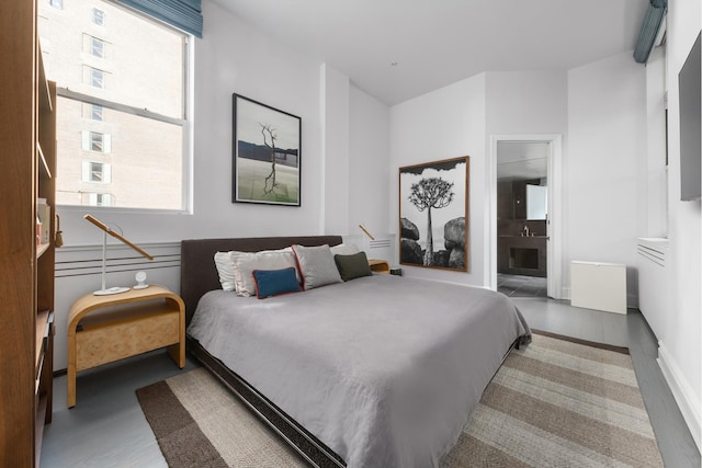 bedroom with baseboards, multiple windows, wood finished floors, and ensuite bathroom