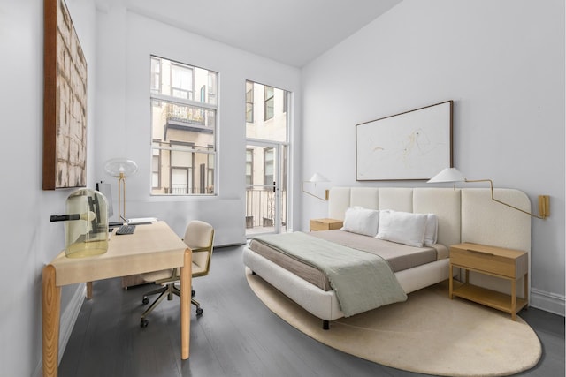 bedroom featuring baseboards, wood finished floors, and access to exterior