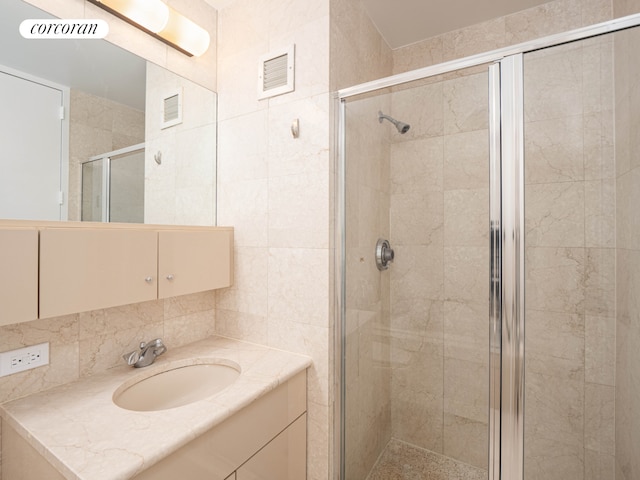 bathroom featuring tile walls, visible vents, a shower stall, and vanity