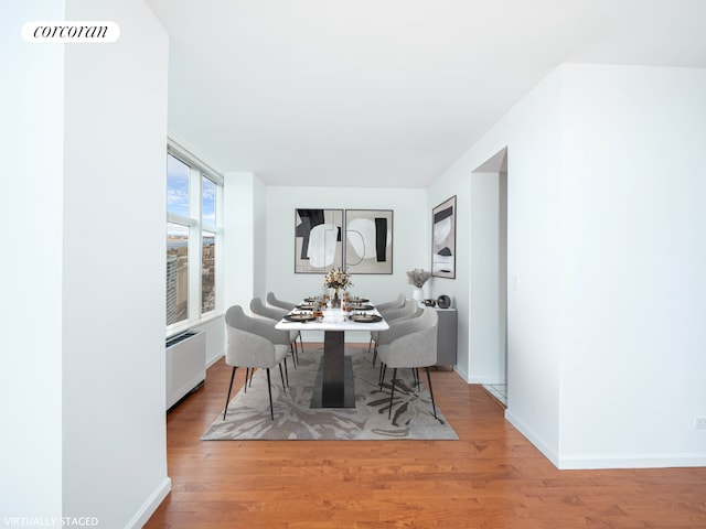 dining space with radiator, wood finished floors, and baseboards