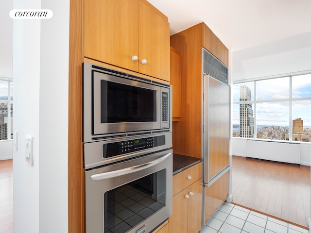 kitchen with a city view, dark stone countertops, light tile patterned floors, and built in appliances