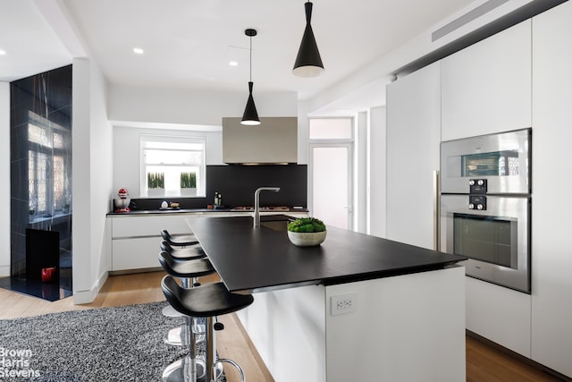 kitchen with dark countertops, stainless steel double oven, white cabinets, and modern cabinets