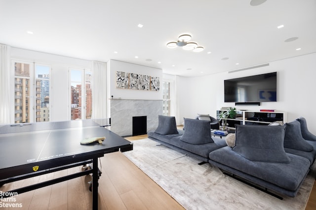 living room featuring recessed lighting, wood finished floors, and a high end fireplace