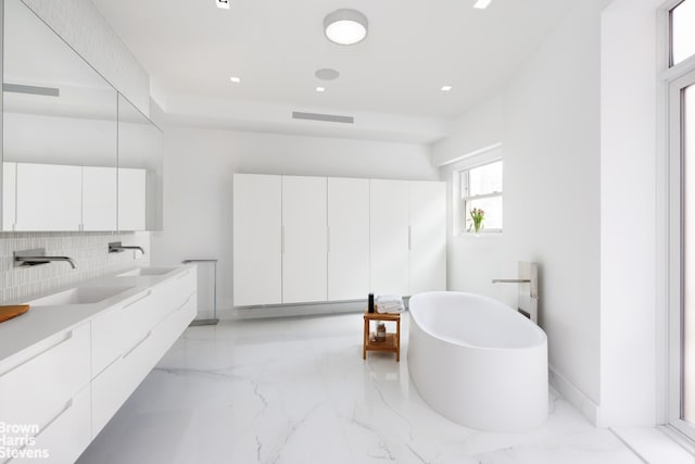 171 W 71st St Unit 9/10A, New York City, NY 10023 - bathroom with marble tiled flooring, backsplash, a freestanding tub, double vanity, and recessed lighting