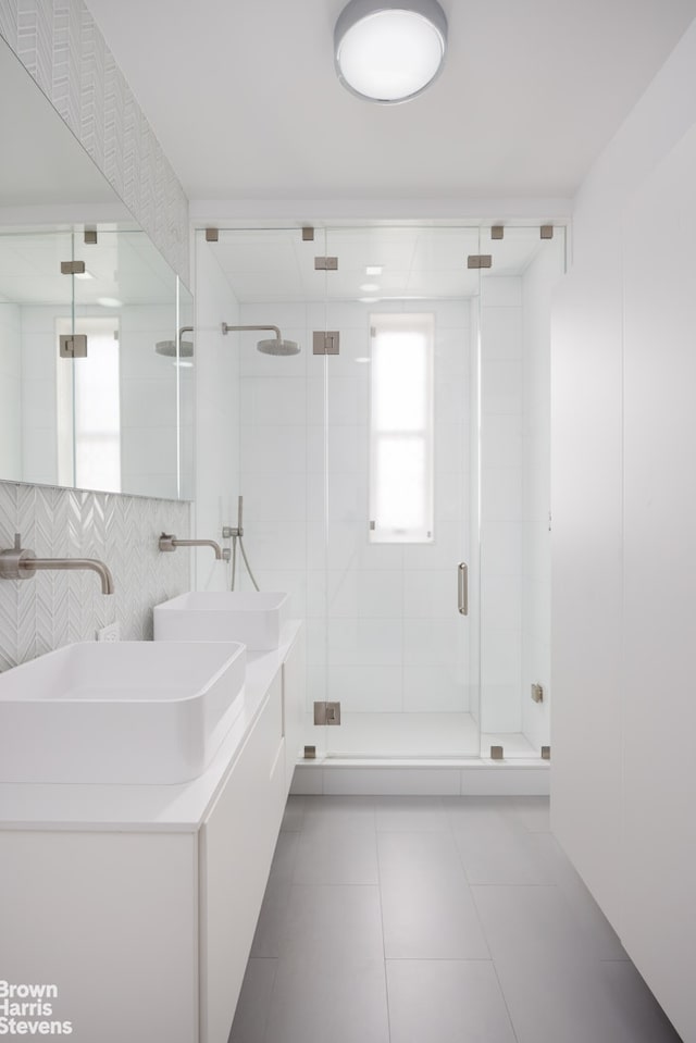 full bathroom featuring a sink, double vanity, a stall shower, and tile patterned floors