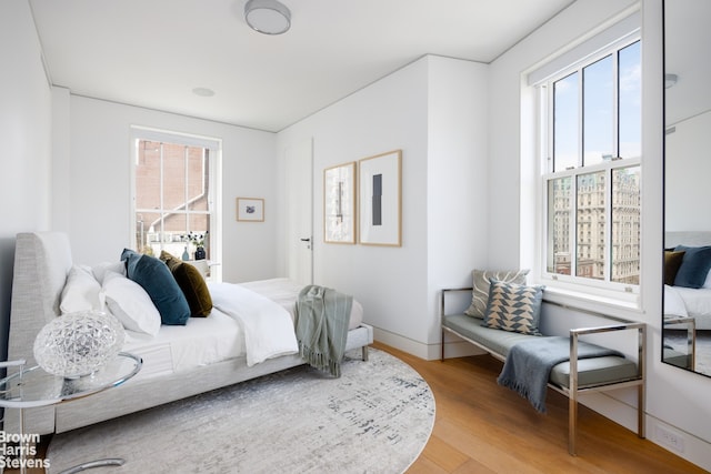 bedroom with multiple windows, wood finished floors, and baseboards