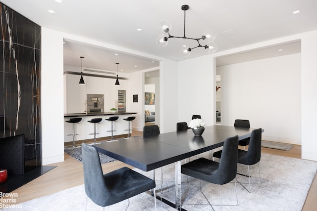 dining area with light wood-style flooring, a notable chandelier, recessed lighting, and baseboards