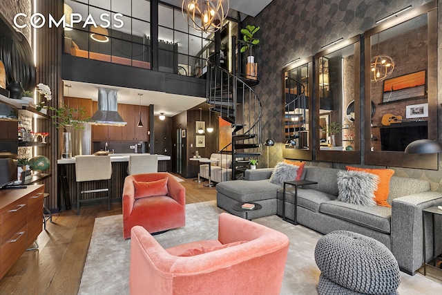 living room with stairway, a notable chandelier, wood finished floors, and a high ceiling