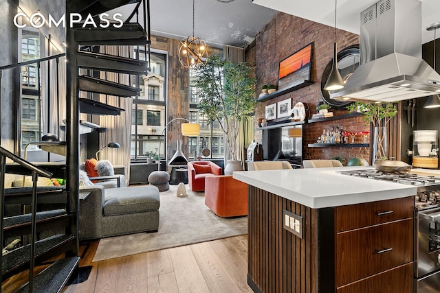 kitchen with a wealth of natural light, high end stainless steel range oven, wood finished floors, and island range hood