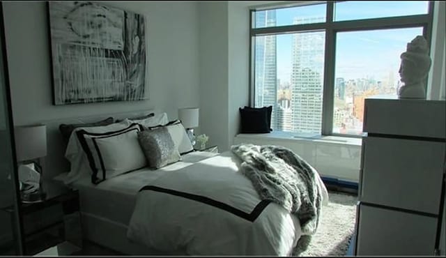 bedroom featuring a city view, multiple windows, and freestanding refrigerator