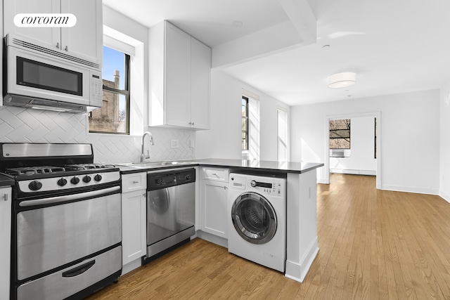 305 W 150th St Unit 501, New York City, NY 10039 - kitchen featuring stainless steel appliances, washer / clothes dryer, a sink, a peninsula, and dark countertops