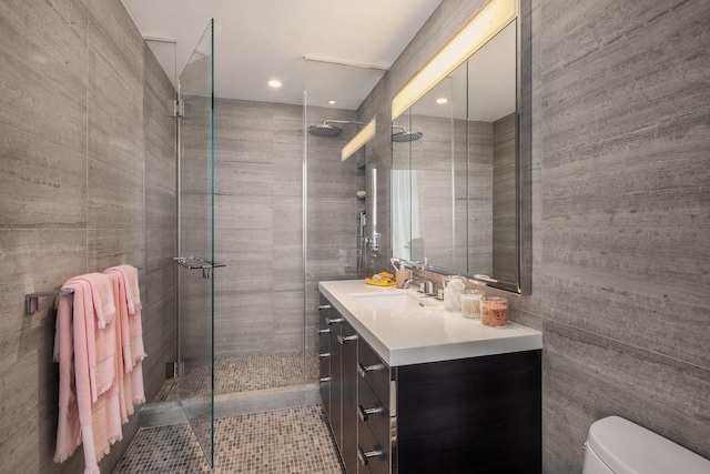 bathroom with tiled shower, toilet, tile walls, and vanity