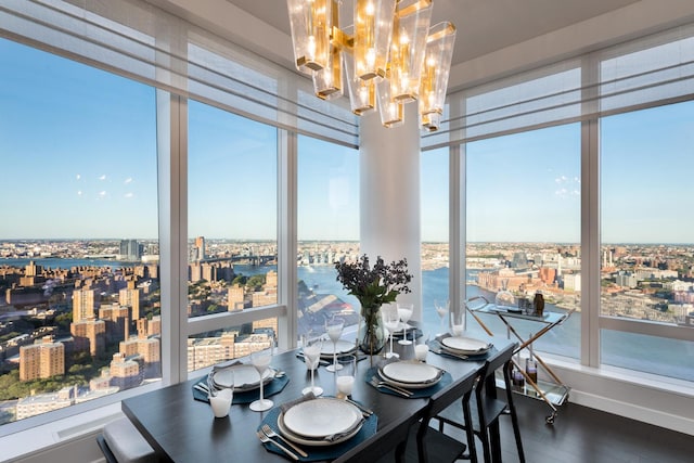 sunroom with an inviting chandelier, a view of city, and a water view