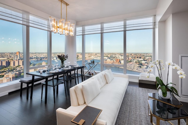 living area with a view of city, a notable chandelier, dark wood-style flooring, and a water view