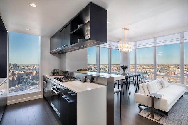 kitchen with modern cabinets, dark wood finished floors, stainless steel gas stovetop, an inviting chandelier, and light countertops