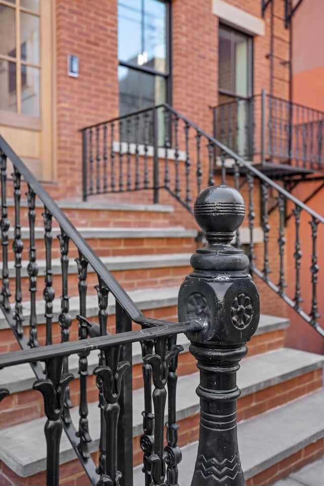 stairway featuring a high ceiling and brick wall