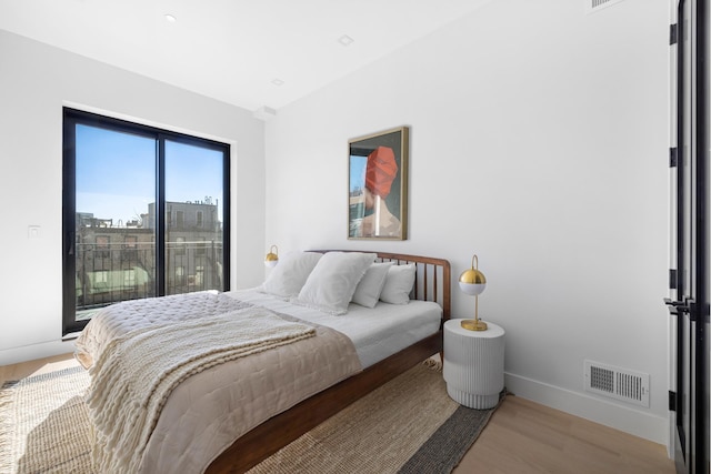 bedroom featuring access to outside, visible vents, baseboards, and wood finished floors