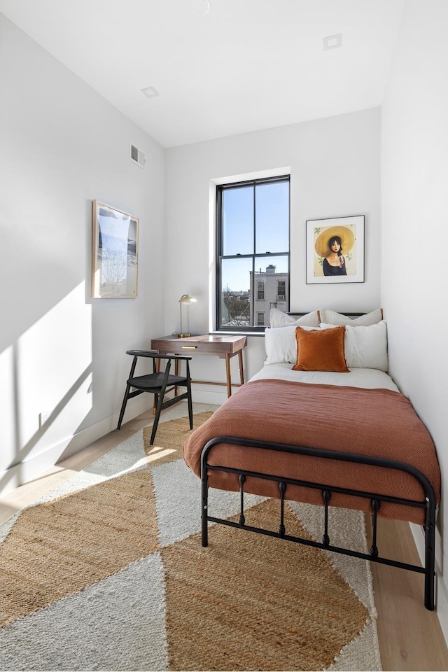 bedroom featuring wood finished floors, visible vents, and baseboards