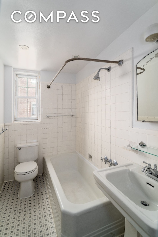 full bathroom with tile walls, shower / bath combination, toilet, and a sink