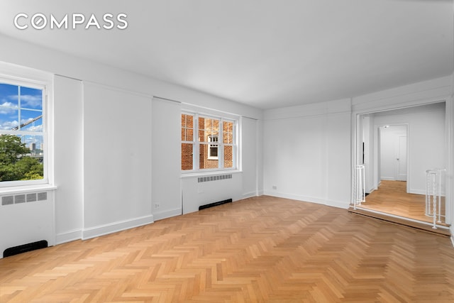 empty room with radiator heating unit and baseboards