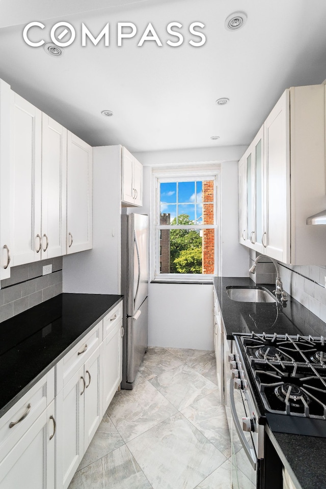 kitchen featuring a sink, stainless steel appliances, white cabinets, marble finish floor, and tasteful backsplash