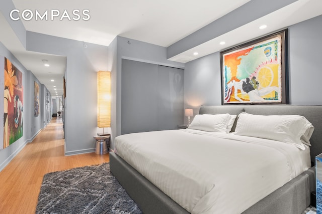 bedroom with wood finished floors, recessed lighting, a closet, and baseboards