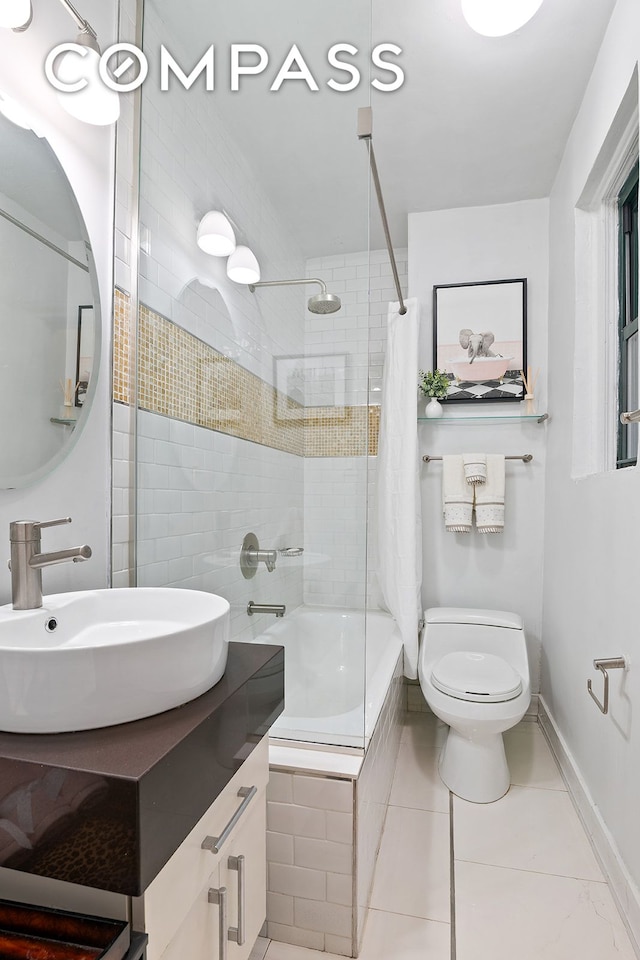 bathroom with tiled shower / bath, tile patterned floors, toilet, baseboards, and vanity