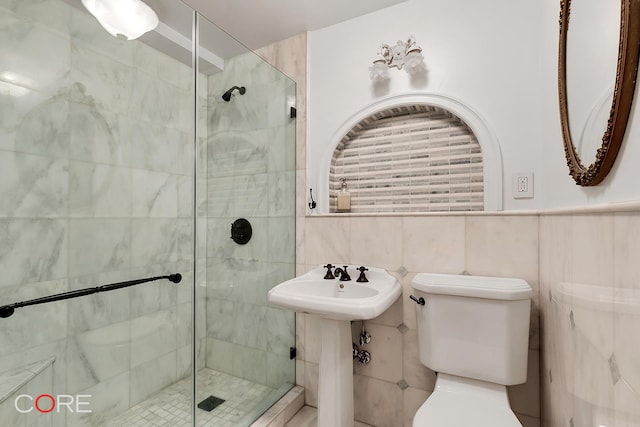 bathroom with tile walls, toilet, and a stall shower