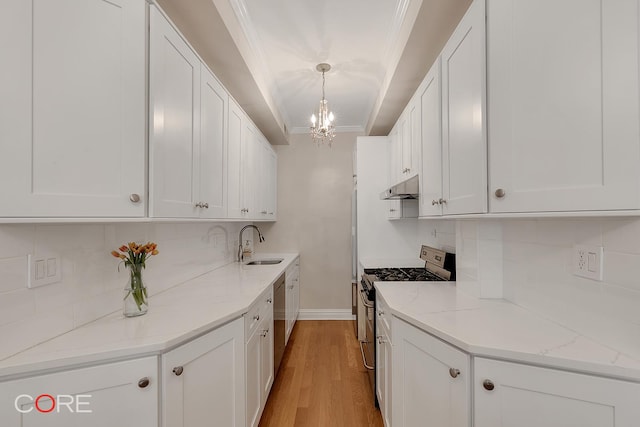 kitchen featuring crown molding, under cabinet range hood, an inviting chandelier, stainless steel appliances, and a sink