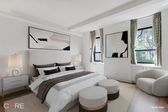 bedroom with beamed ceiling, multiple windows, baseboards, and wood finished floors