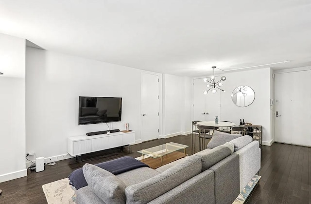 living area with a chandelier, baseboards, and dark wood finished floors