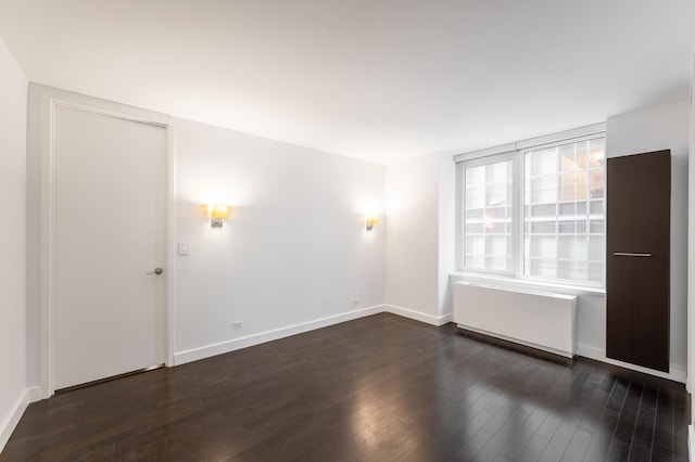 empty room featuring dark wood finished floors and baseboards