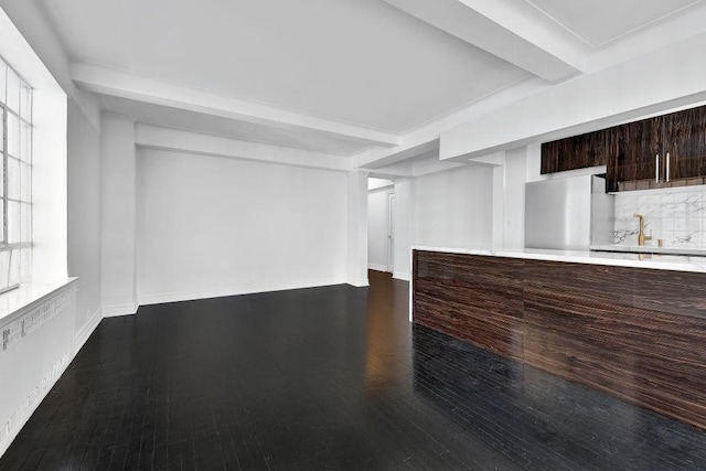 unfurnished living room featuring a sink, beamed ceiling, baseboards, and dark wood-style flooring