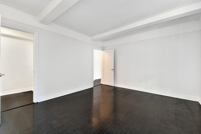 spare room featuring baseboards, beam ceiling, and dark wood finished floors