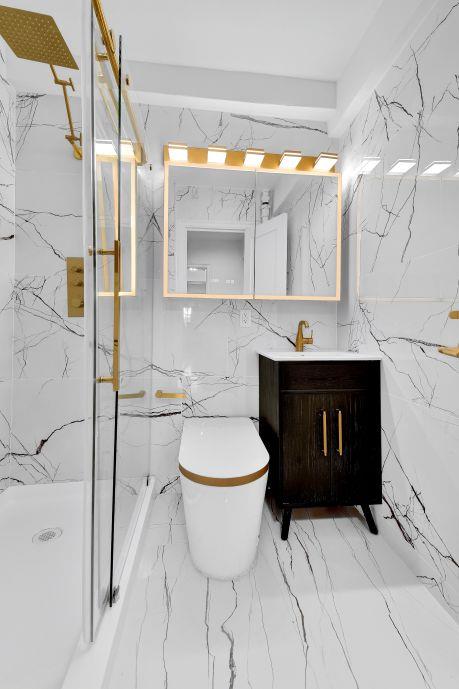 bathroom featuring vanity, stone wall, a marble finish shower, toilet, and marble finish floor