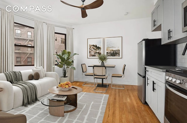 living room featuring a ceiling fan, light wood-type flooring, and baseboards