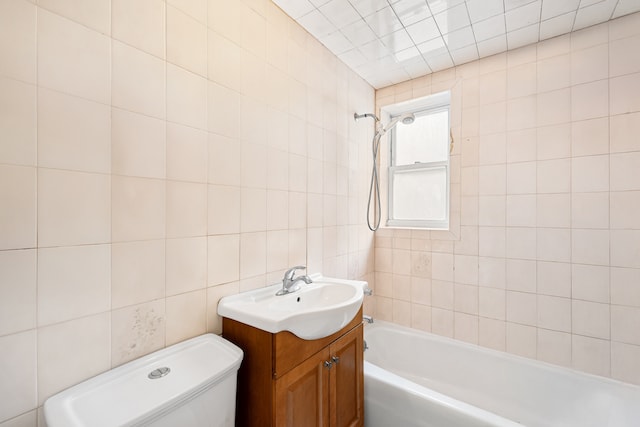 bathroom featuring toilet, vanity, tile walls, and bathing tub / shower combination