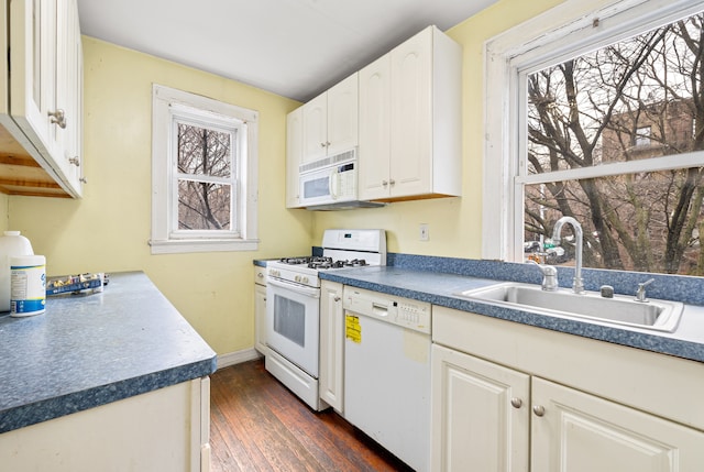 kitchen with white appliances, baseboards, dark wood-style flooring, a sink, and dark countertops