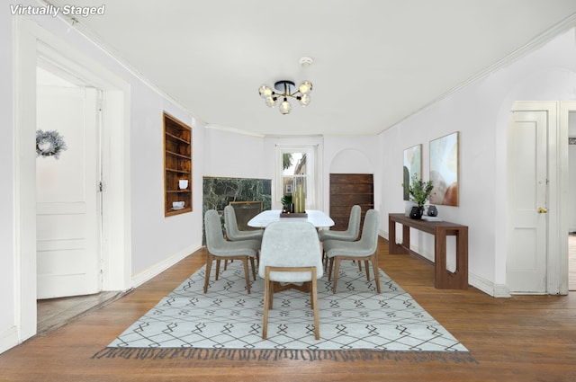 dining space with baseboards, a notable chandelier, wood finished floors, and ornamental molding