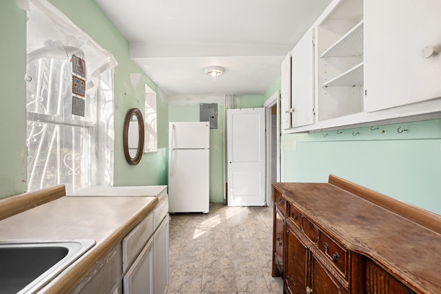 kitchen with open shelves, a sink, white cabinetry, freestanding refrigerator, and light countertops