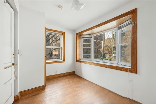 spare room with baseboards and light wood-type flooring