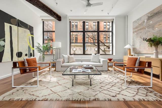 living room featuring beam ceiling, radiator heating unit, a ceiling fan, and wood finished floors