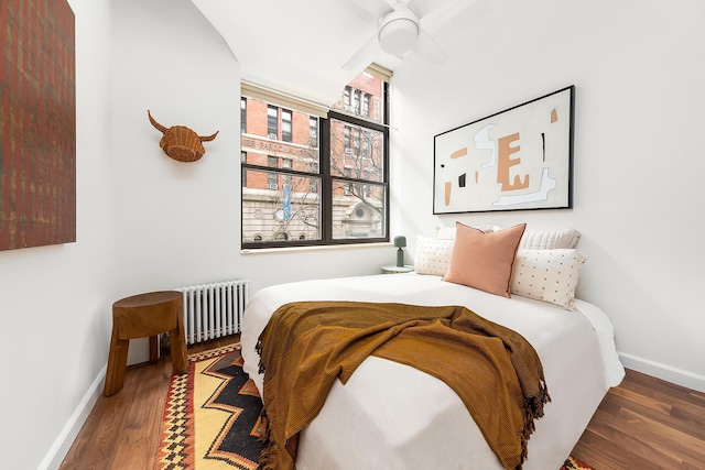 bedroom featuring baseboards, radiator, wood finished floors, and a ceiling fan