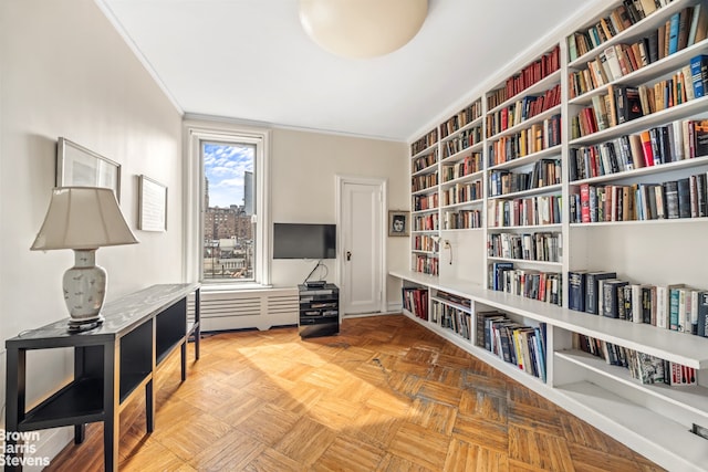 living area with crown molding and wall of books